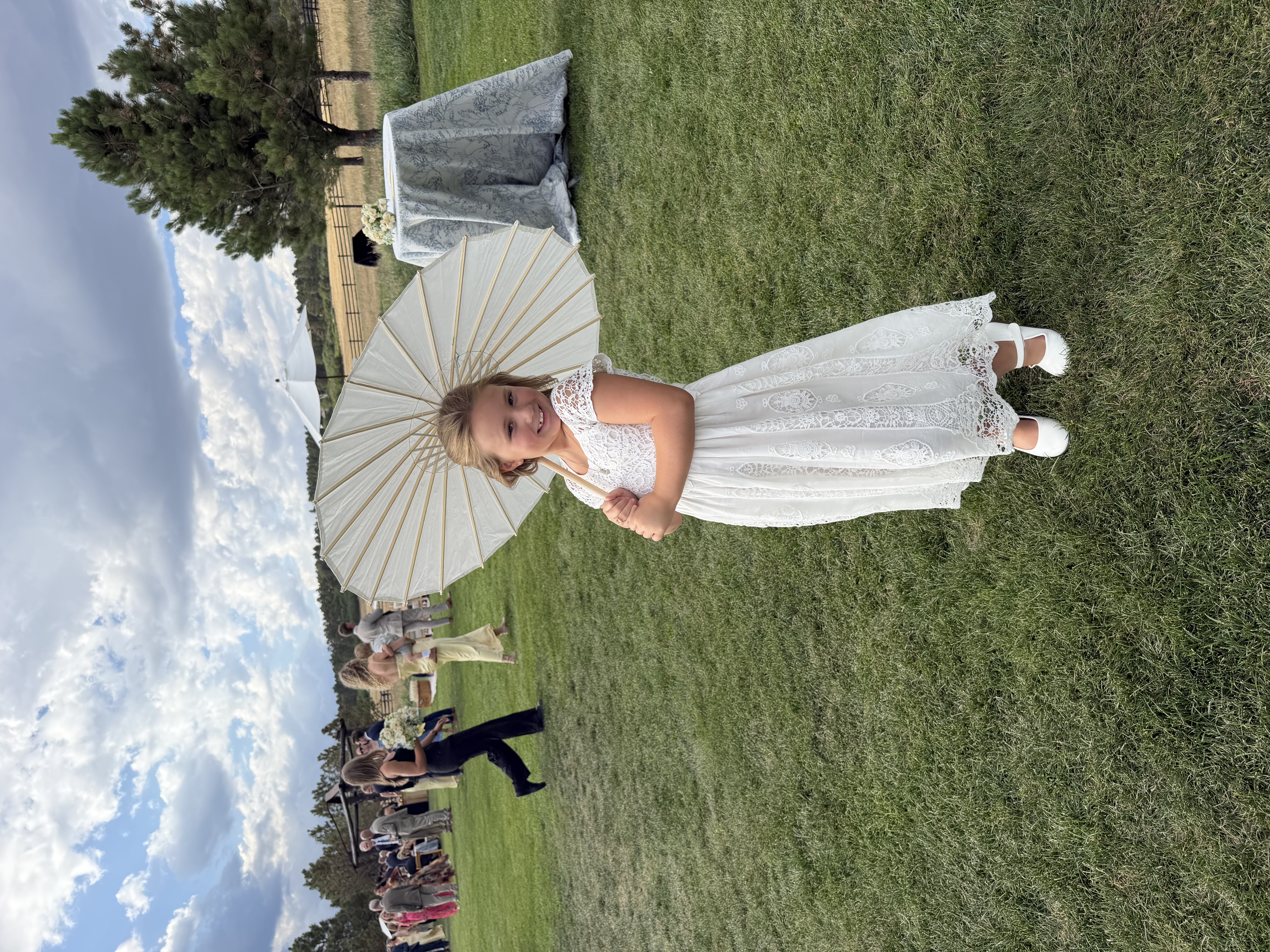 Lily as a flower girl at a wedding, holding a parasol